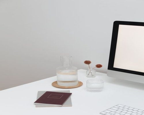 Glass of water resting on a clean work desk next to a notebook